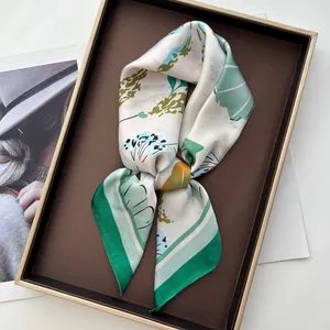 Green and white floral faux silk scarf with botanical shell prints on a display tray