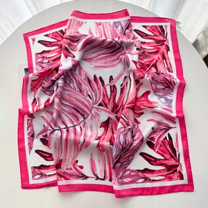 Detailed view of monstera leaf print on silk-like scarf with magenta edges and satin finish