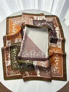 Detailansicht des Seidenschals mit Paisley-Muster und elegantem Rollsaum auf dem Tisch