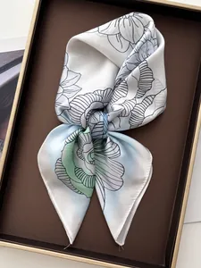 Vue détaillée d'un foulard en soie à fleurs avec bords roulés sur un plateau