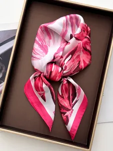Detailed shot of pink satin scarf with tropical leaf pattern on a display tray