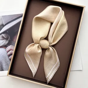 Champagne polka dot silk-feel square scarf tied in a bow on a luxury display tray