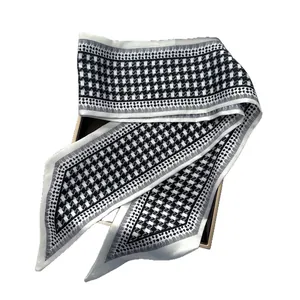 Élégant foulard en soie pied-de-poule noir et blanc drapé sur un coffret cadeau chic