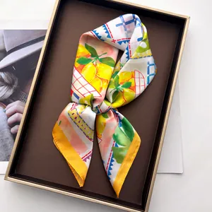 Detail eines Seidengefühl-Schals mit Zitronenprint in einer hochwertigen Geschenkbox