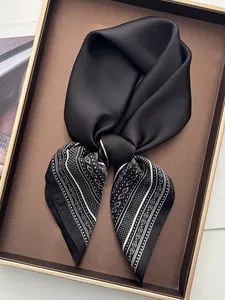 Close-up of knotted black silk scarf featuring paisley print and polka dot details