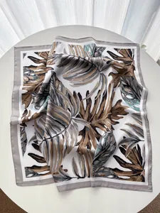Close-up of tropical monstera leaf print on elegant silk square scarf with rolled edges