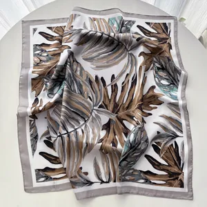 Detailed view of monstera leaf print on silky scarf with grey border and satin finish