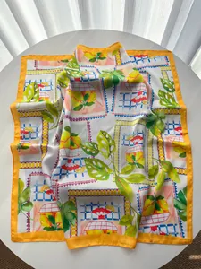 Detail eines Seidenschals mit lebhaftem Zitronendruck und gelbem Rollsaum