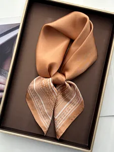 Close-up of bronze silk scarf with white paisley patterns on a luxury display tray