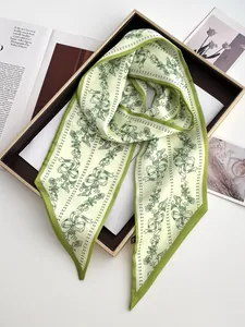 Detailed macro of green plant print satin scarf neatly folded in a decorative tray