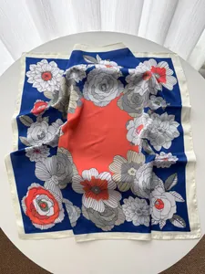 Détail de l'élégant foulard en soie aux motifs éclatants bleu marine et corail