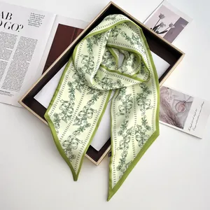Detail of green floral skinny silk scarf with bow pattern on brown display tray