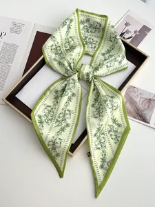 Detail of light green twilly scarf with floral prints tied in a bow on a display tray