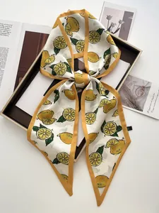 Détail d'un foulard élégant en satin à imprimé citron noué dans un coffret cadeau