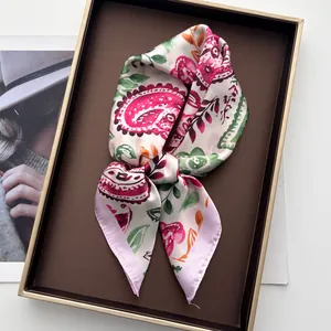 Vue détaillée d'un foulard en soie à imprimé paisley dans une boîte cadeau marron