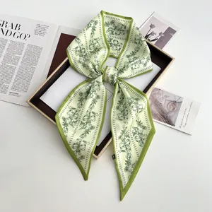 Detailed view of floral silk twilly tied in a bow on a tray with lifestyle props