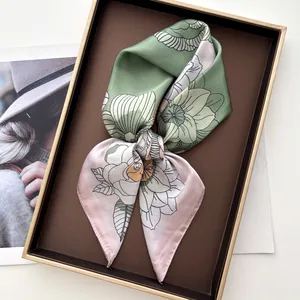 Vue détaillée d'un foulard en soie à fleurs rose et vert dans une boîte cadeau de luxe