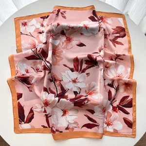 Detail of elegant pink silk square scarf with floral print and bronze border on table