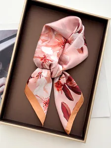 Detailed view of floral silk scarf with pink cherry blossoms in a brown gift box