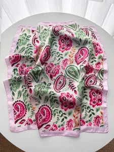Détail d'un foulard en soie à motif cachemire rose et vert avec texture satinée