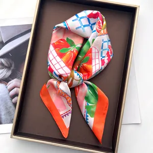 Detailansicht eines Seidenschals mit Orangen-Print in einer eleganten Geschenkbox