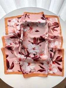 Detail of elegant peach blossom silk scarf with orange satin edge on white table