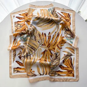 Close-up of tropical monstera leaf print on a white faux silk square scarf with satin finish