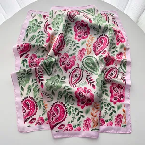 Détail d'un foulard en soie à motif paisley rose et vert avec une texture brillante