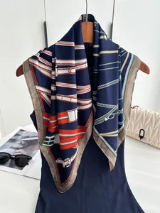 Close-up of luxury navy silk scarf with gold chain and red strap pattern on wood hanger
