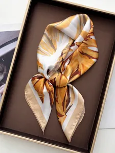 Detail of silk square scarf featuring yellow floral patterns and smooth satin texture