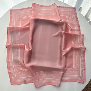 Detailed macro view of pink silk square scarf featuring intricate paisley edge patterns