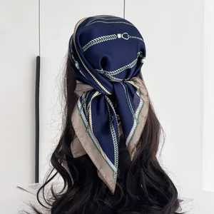 Detail view of the silk scarf tied as a headscarf with chain and belt print pattern