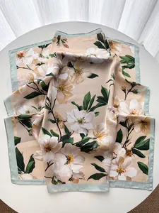 Close-up of elegant silk square scarf with floral print and light green border detail