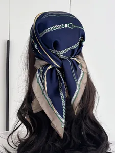 Detail of silk-feel navy blue scarf with chain pattern worn as an elegant headscarf