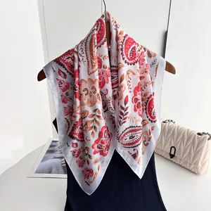 Détail macro d'un foulard carré soyeux avec motifs paisley rouges sur fond blanc