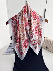Détail d'un carré de soie imprimé paisley rouge et orange sur un cintre chic