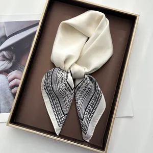 Detail view of paisley print silk scarf presented in a premium gold-trimmed gift box