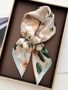 Detail of floral silk scarf in beige with peach blossom print and fine green hem finish