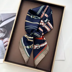 Detail of silk scarf with equestrian chain print on a leather tray with magazine