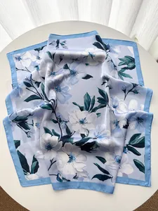Close-up of floral print silk scarf in light blue with elegant blossom patterns