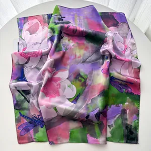 Macro detail of silk floral scarf showing lotus print and smooth satin texture edge