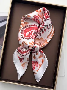Détail d'un foulard en soie imprimé paisley avec motifs floraux orange et rouge vifs
