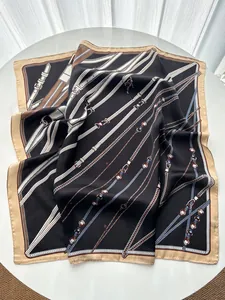 Detail view of square silk scarf with vintage chain and leather belt print on white surface