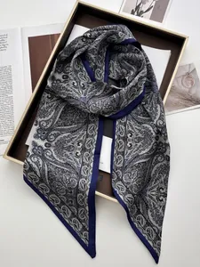 Detail of elegant paisley satin scarf with navy blue border presented in a luxury gift box