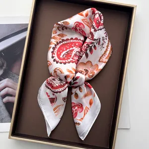 Détail d'un foulard en soie paisley plié dans un coffret cadeau au fini satiné