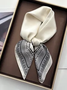 Detailed view of silk square scarf with black paisley prints on cream satin fabric