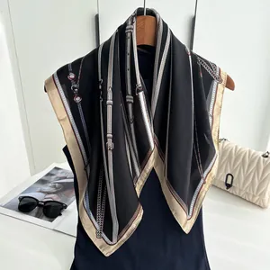 Detail of elegant chain and leather belt print on a black silk-feel square scarf