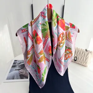 Detail eines Seidenschals mit Orangen- und Monstera-Print auf einem Kleiderbügel