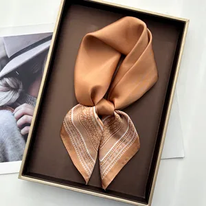 Elegant orange-brown paisley silk square scarf with satin luster on a display tray