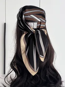 Detail of silk scarf with chain pattern tied as a headband on brunette wavy hair